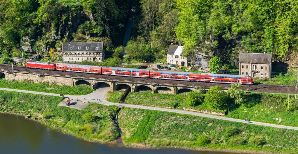 Nachhaltig reisen mit der Bahn, Zug neben der Elbe über einem Viadukt